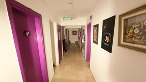 Un couloir avec des portes violettes, un extincteur et des œuvres d’art encadrées accrochées aux murs.