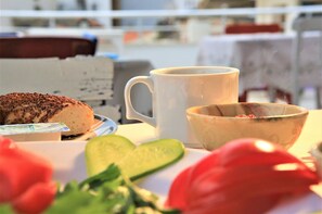 A breakfast setting with a sandwich, a mug, a bowl, and fresh vegetables. - Lavender Otel (Cesme)