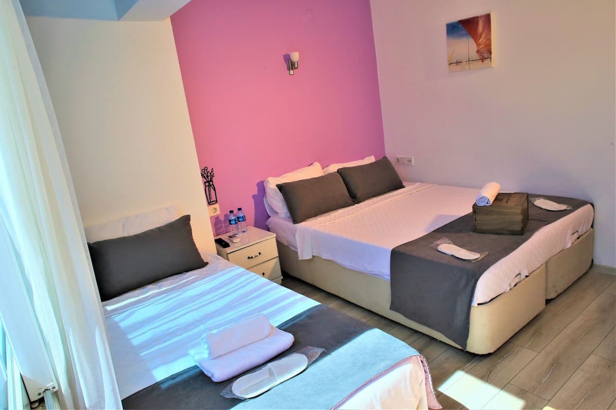 A bedroom with two beds, a nightstand with a lamp, and a wall-mounted light fixture.