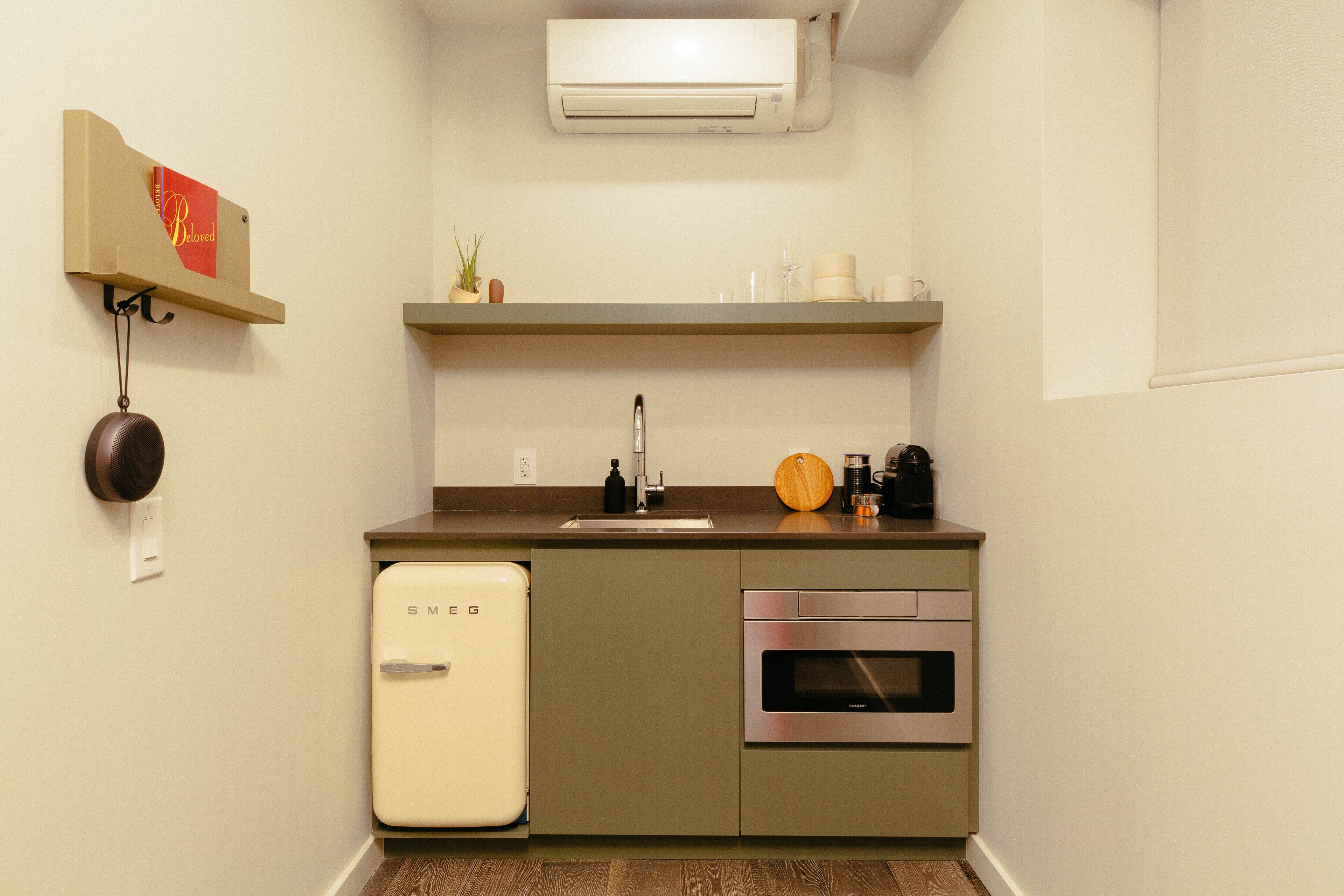 Una cocina compacta con refrigerador, horno y pileta.