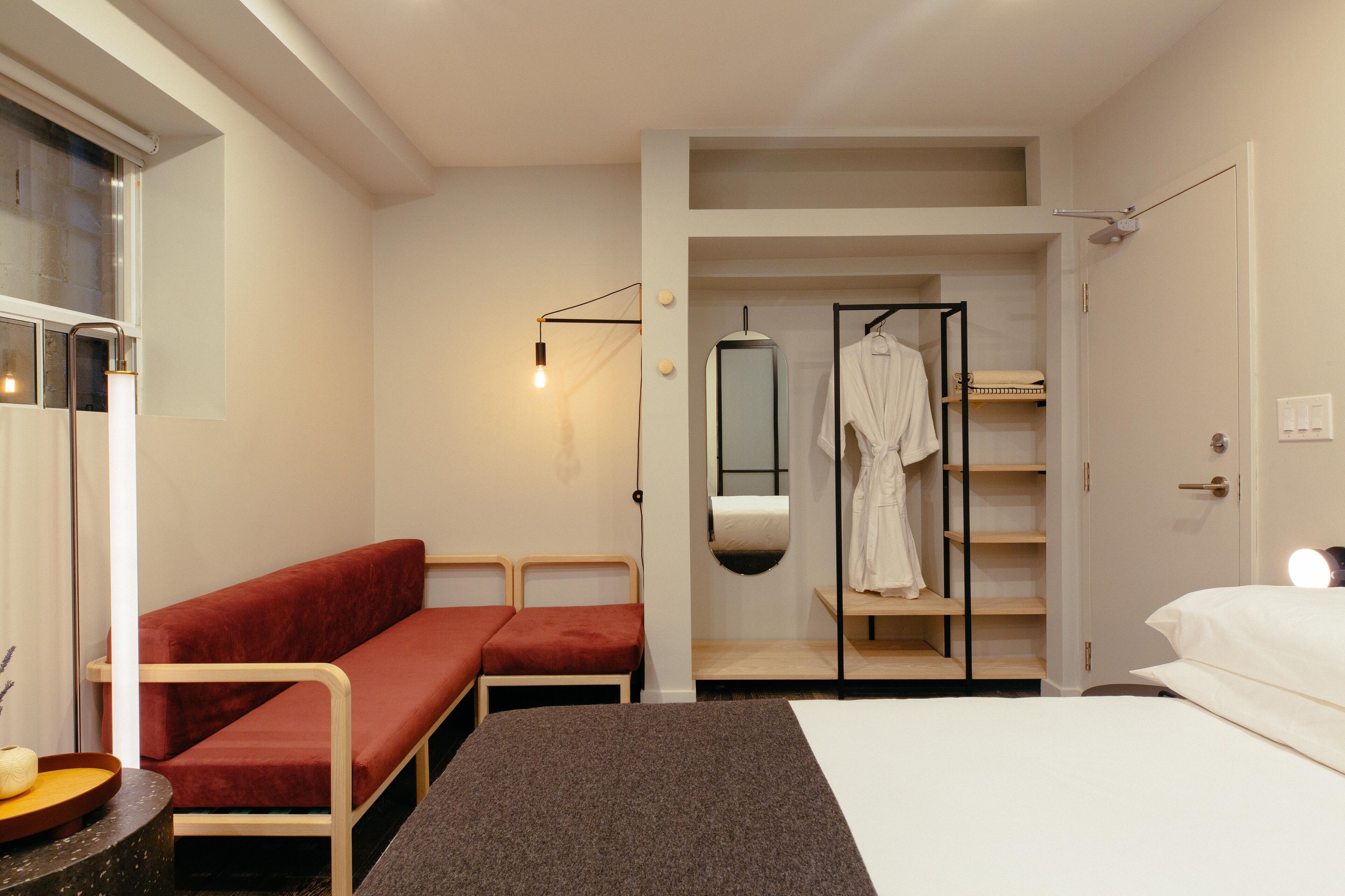Una habitación de hotel moderna con cama, zona de estar, armario y espejo.