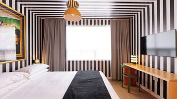 Una habitación de hotel con una cama, un escritorio, un televisor y una ventana con cortinas.
