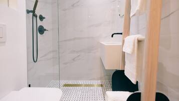 A modern bathroom with a glass-enclosed shower, a white sink, and a black toilet.
