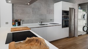 Una cucina moderna con una grande isola centrale, elettrodomestici integrati e un'isola caratterizzata da una ciotola in legno originale.