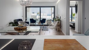 Un soggiorno moderno con un tavolo da pranzo in vetro, sedie blu e una lampada a sospensione.