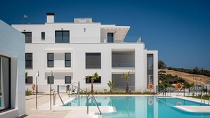 Un edificio moderno con piscina, diversi balconi e una vista aperta sul paesaggio circostante.