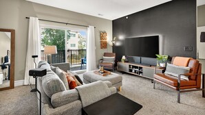 A modern living room with a sofa, armchair, and TV stand.