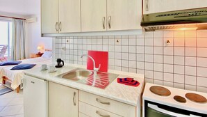 Una cuina moderna amb armaris blancs, un taulell vermell i una placa de cocció.