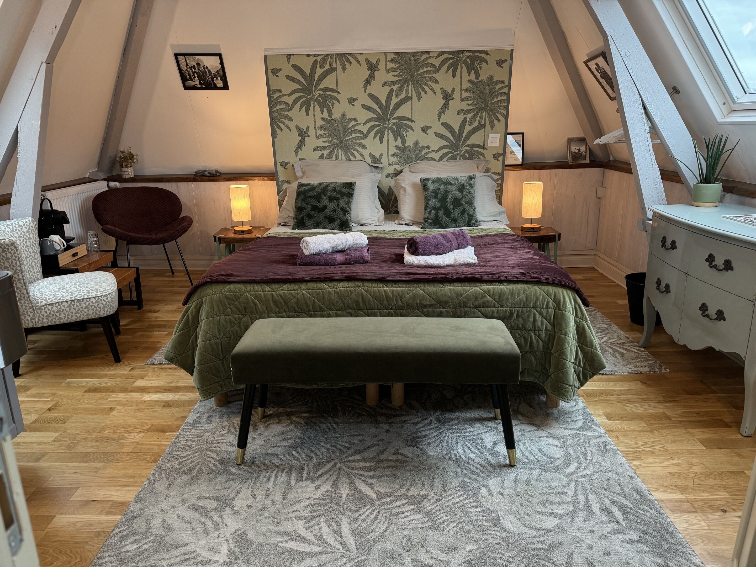 A cozy bedroom with a bed, a chair, a dresser, and a nightstand.