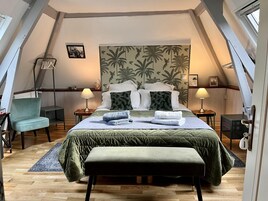 Un dormitorio acogedor con cama, dos mesitas de noche, una silla, un banco y un ventanal grande.