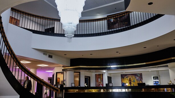 A multi-level interior with a grand chandelier, a reception desk, and a staircase. - The McLure Hotel and Conference Center (Wheeling)