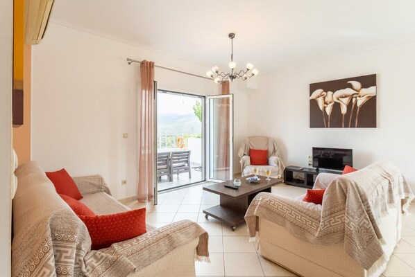 A modern living room with two sofas, a coffee table, a TV, and a balcony with a view. - Villa Europe Ena - Two Bedroom Villa, Sleeps 4 (Ionian Islands)