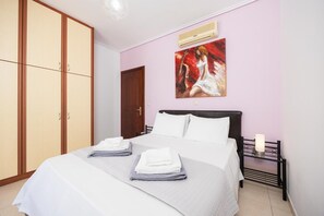 Un dormitorio con cama, armario, aire acondicionado y un cuadro en la pared.