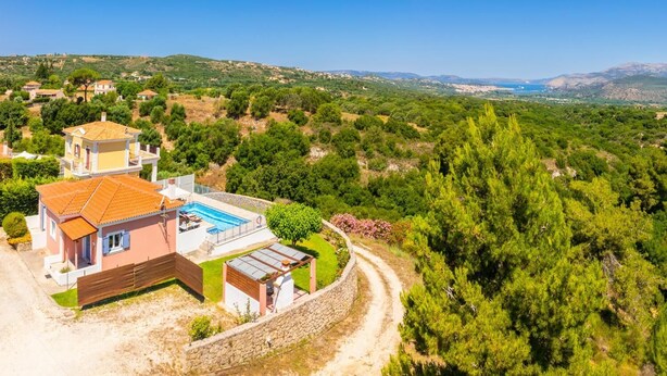 Una casa a due piani con piscina, immersa nel verde e circondata da colline.