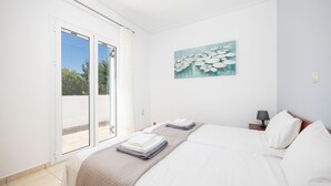 Una camera d'hotel con un letto, un quadro, un comodino e vista attraverso una porta scorrevole.