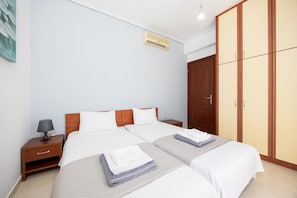 A hotel room with two beds, a wardrobe, a nightstand, and an air conditioning unit. - Villa Europe Ena - Two Bedroom Villa, Sleeps 4 (Ionian Islands)