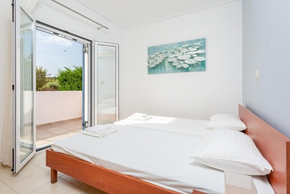 A bedroom with a bed, a painting, and a sliding glass door leading to a balcony. - Villa Europe Ena - Two Bedroom Villa, Sleeps 4 (Ionian Islands)