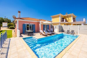 Una propiedad residencial con piscina, mobiliario exterior y un patio cubierto.