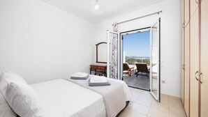 Una camera da letto con un letto, un comodino, una cassettiera e un balcone con vista.