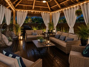 An outdoor patio with wicker furniture, a wooden deck, and string lights.
