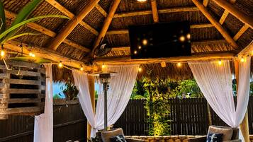 An outdoor patio with a wooden ceiling, wicker furniture, and string lights.