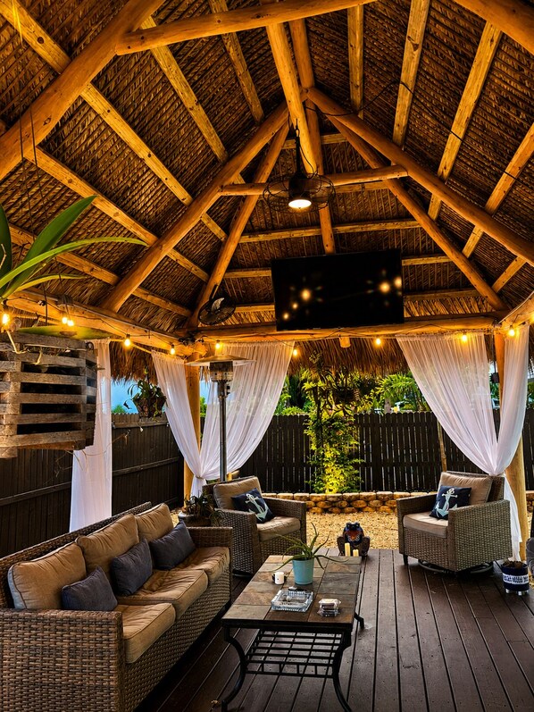 An outdoor patio with a wooden ceiling, wicker furniture, and string lights.