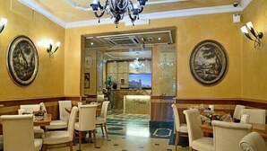 A hotel lobby with a reception desk, seating area, and decorative wall paintings. - Hotel Homs (Rome)