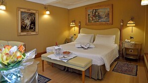 A hotel room with a large bed, bedside tables, a desk with a chair, and two paintings on the walls. - Hotel Homs (Rome)