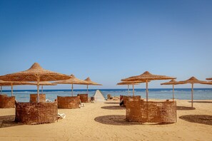 Privat strand, hvit sand, solsenger og parasoller
