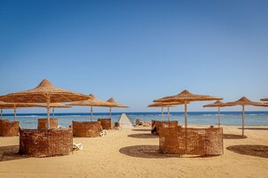 Playa privada, arena blanca, sillas reclinables de playa, sombrillas