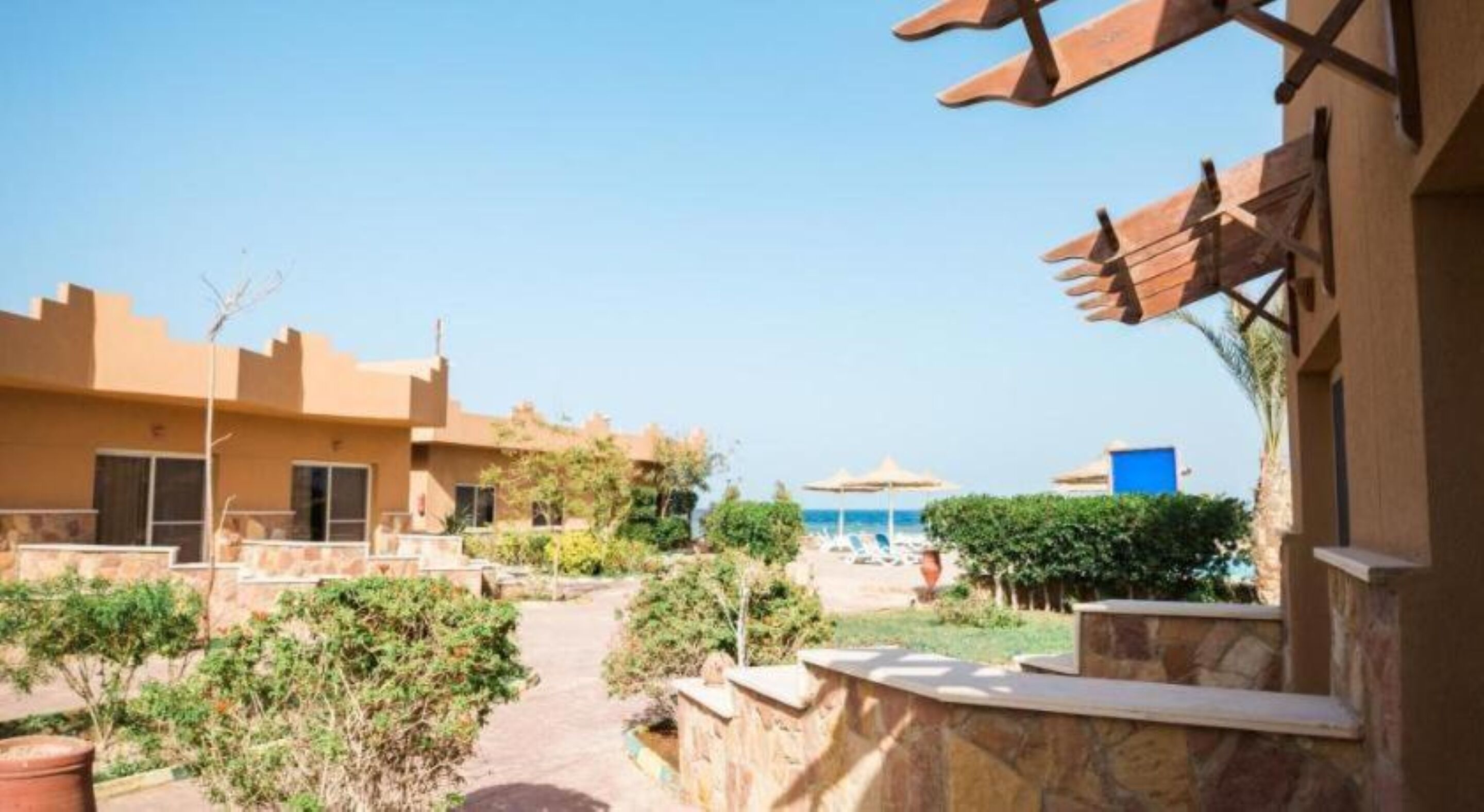 Ein Resort mit mehreren Gebäuden, einem Weg zu einem Strandbereich und freiem Blick auf das Meer.