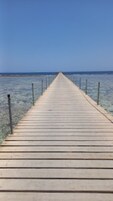 Un muelle de madera que se adentra en el mar, con barandillas a ambos lados.
