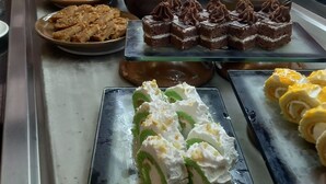 A variety of desserts displayed on a counter with a view of the outdoors through a window. - Silver Beach Boutique Hotel (El Quseir)
