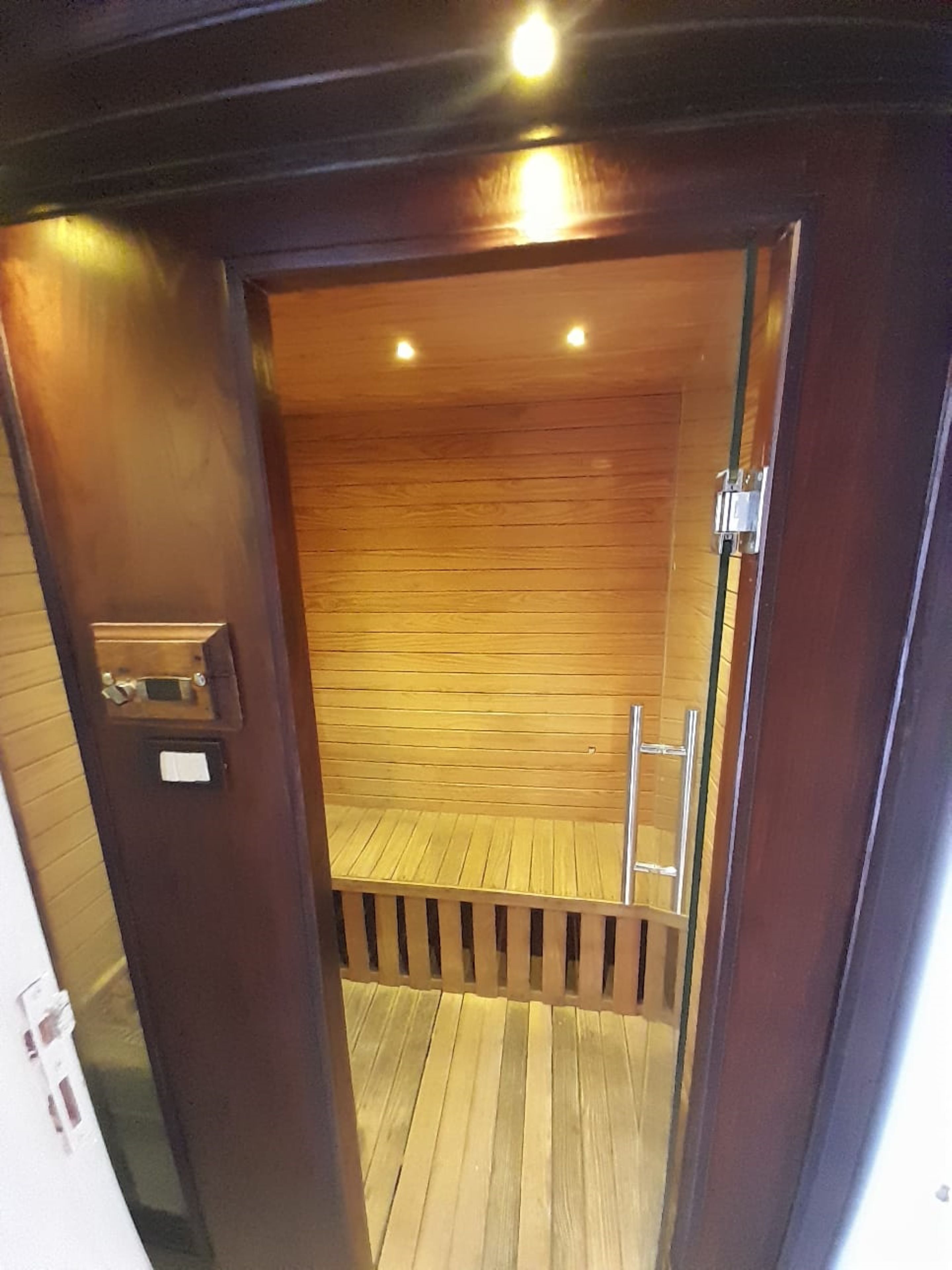 A wooden interior with a wooden floor, a metal ladder, and a door with a handle and lock.