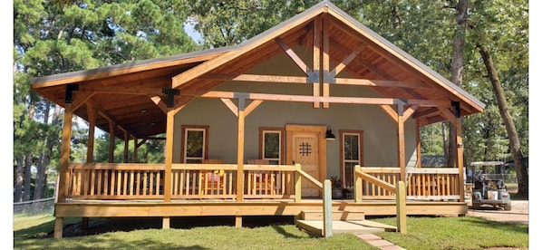 Une cabane en bois avec une véranda, une porte et une fenêtre.