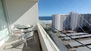 A balcony with a table and chairs, overlooking a building and a body of water. - Departamento con Piscina y Spa en la Serena (La Serena)