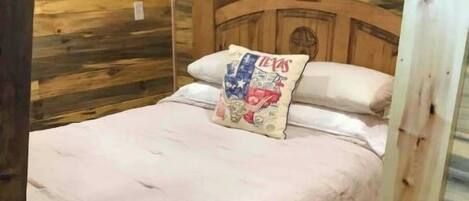 A wooden-paneled bedroom with a bed, pillows, and a nightstand.