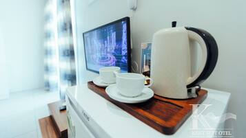 A kitchenette with a coffee maker, two cups, and a digital screen displaying a cityscape.