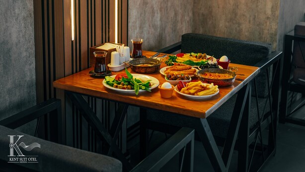 Una mesa de comedor con diversos platos, una vela y un vaso de bebida en un ambiente moderno.