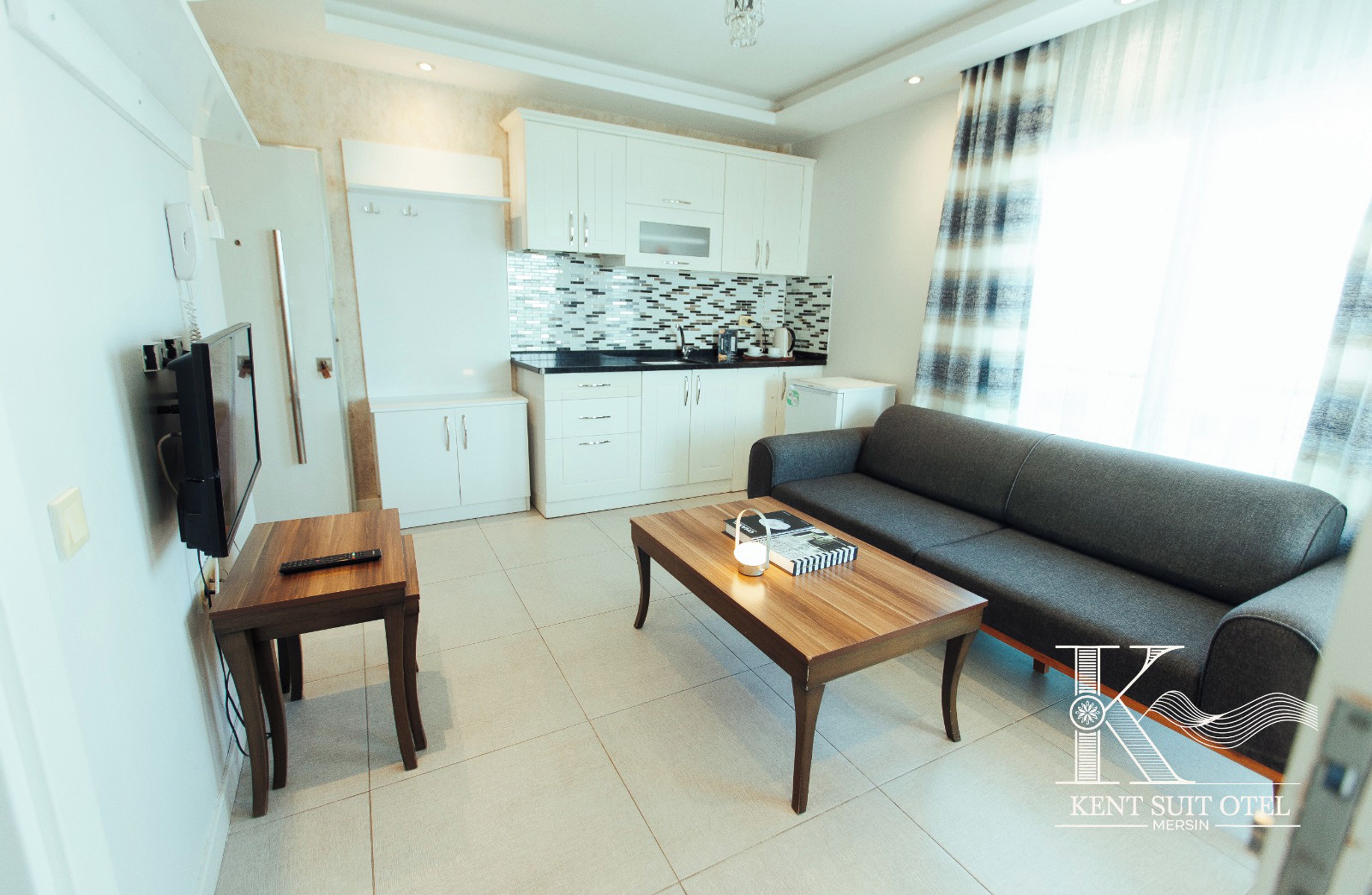A compact living space with a kitchenette, a sofa, a coffee table, and a TV.