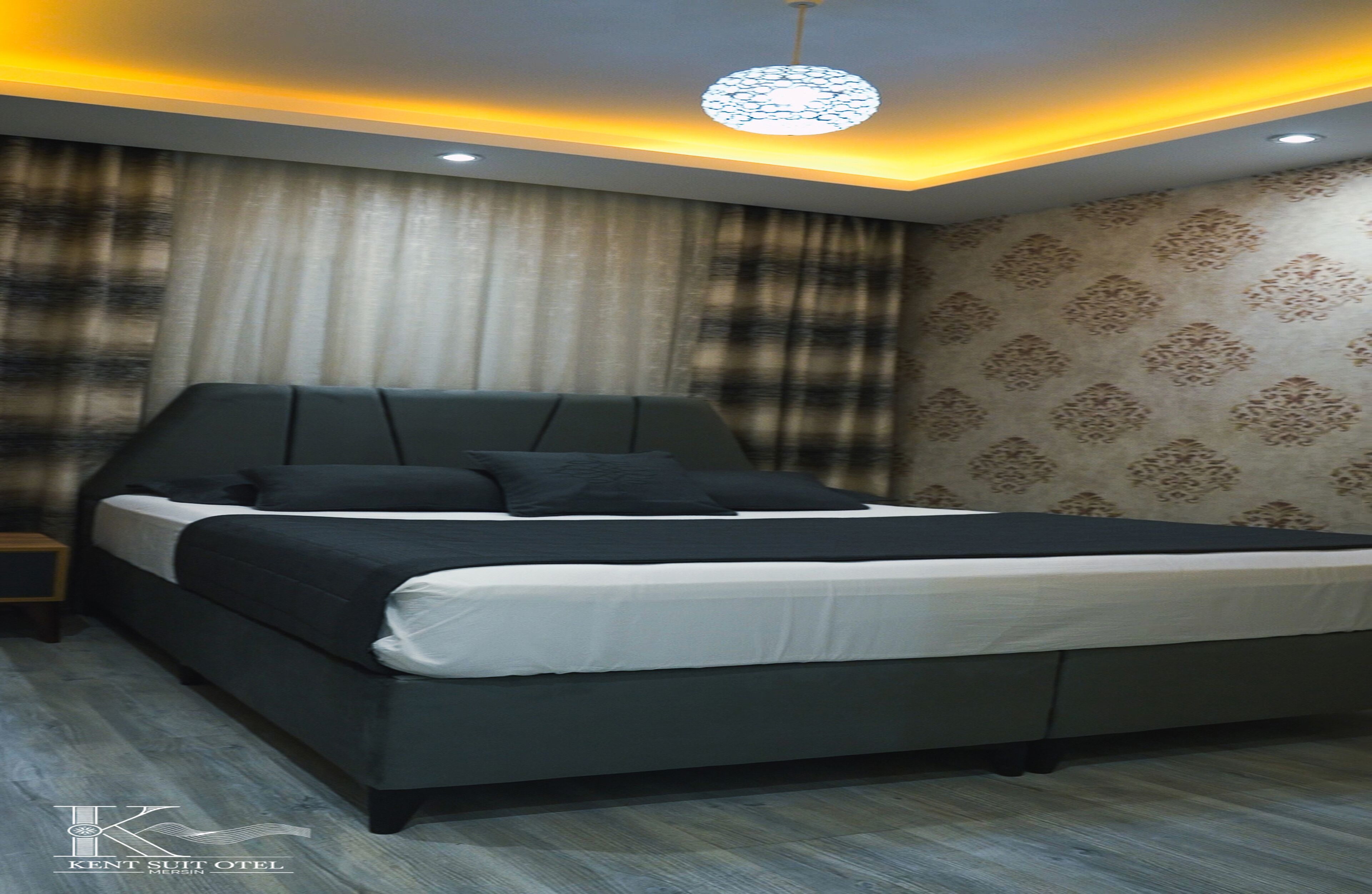 Een moderne slaapkamer met een groot bed, een nachtkastje en een behang met een patroon.