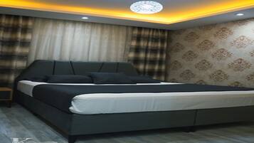 Een moderne slaapkamer met een groot bed, een nachtkastje en een behang met een patroon.