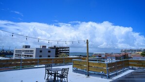 A rooftop terrace with a view of the sea, a wooden fence, and a metal railing. - La Ferreteria Apartments (San Juan)