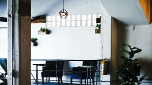 A spacious indoor area with a high ceiling, exposed beams, and a mix of seating arrangements including tables and chairs. - La Ferreteria Apartments (San Juan)