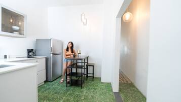 Une cuisine compacte équipée d’un réfrigérateur, d’une machine à café et d’une table avec une chaise.