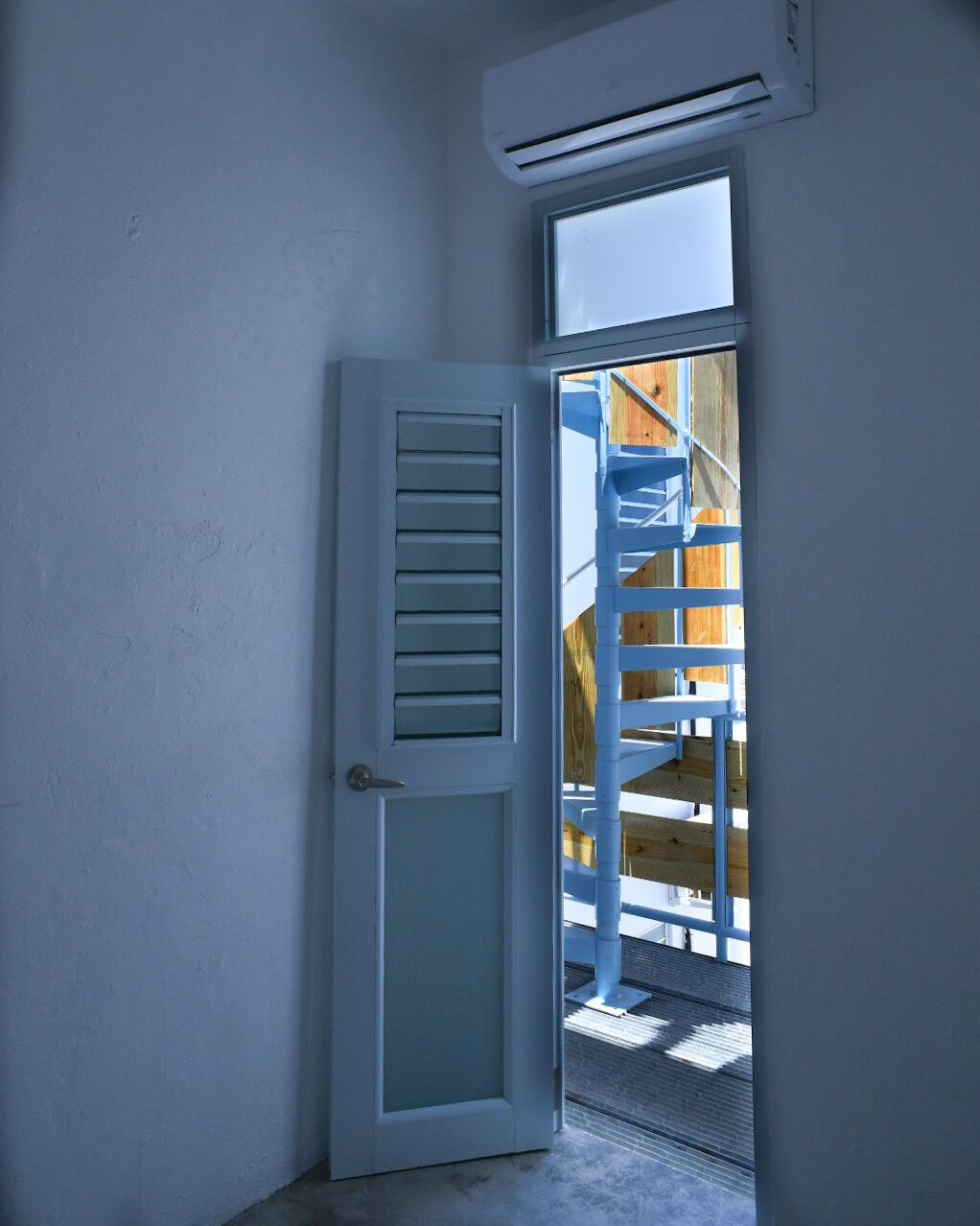 Uma porta dá para uma varanda com vista para um deck de madeira e uma janela acima.