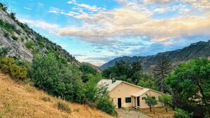 Una casa con techo inclinado, rodeada de árboles y colinas.