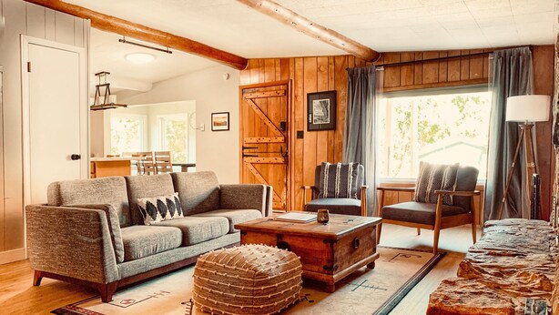 Una sala de estar acogedora con un sofá, sillones, una mesa de centro y una alfombra.