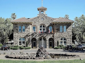 A stone building with a clock tower, arched windows, and flags. - Sonoma Wine Country Luxury Log Cabin (Sonoma)