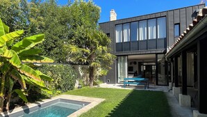 Ein modernes Haus mit Swimmingpool, gepflegtem Rasen und einer Terrassenfläche.